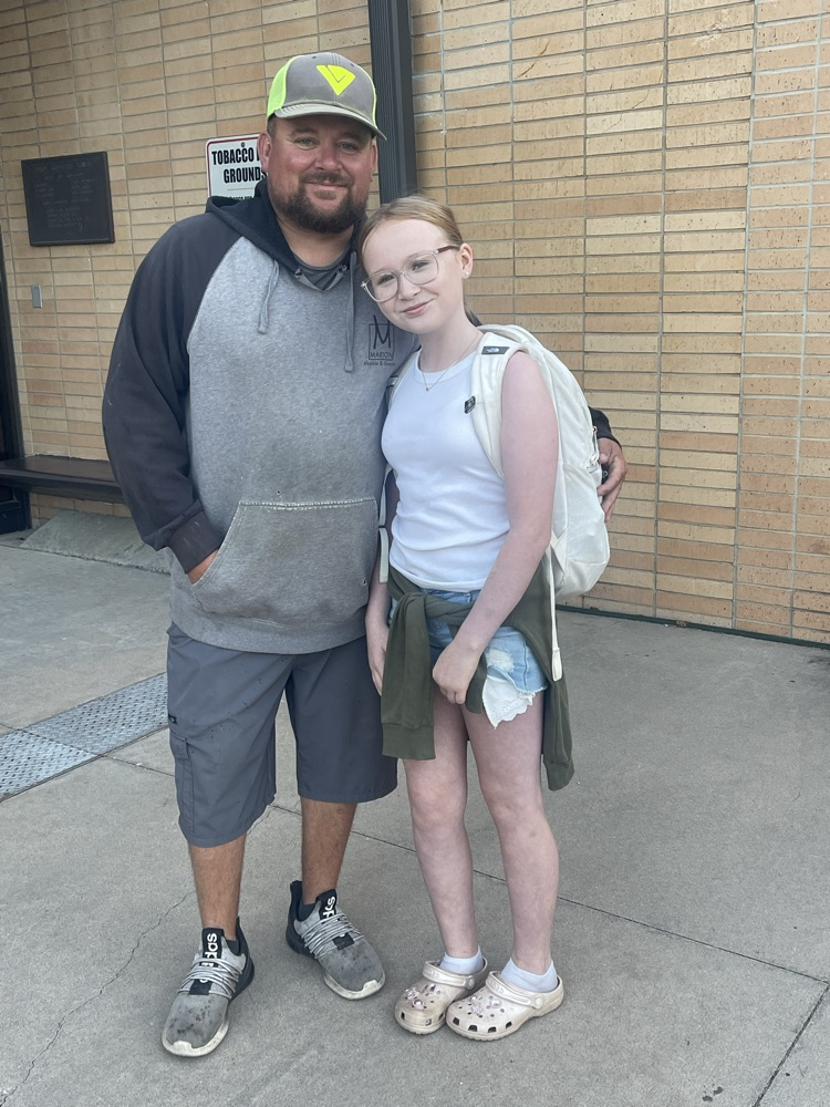 A MES student takes a picture with her dad who was a greeter this morning