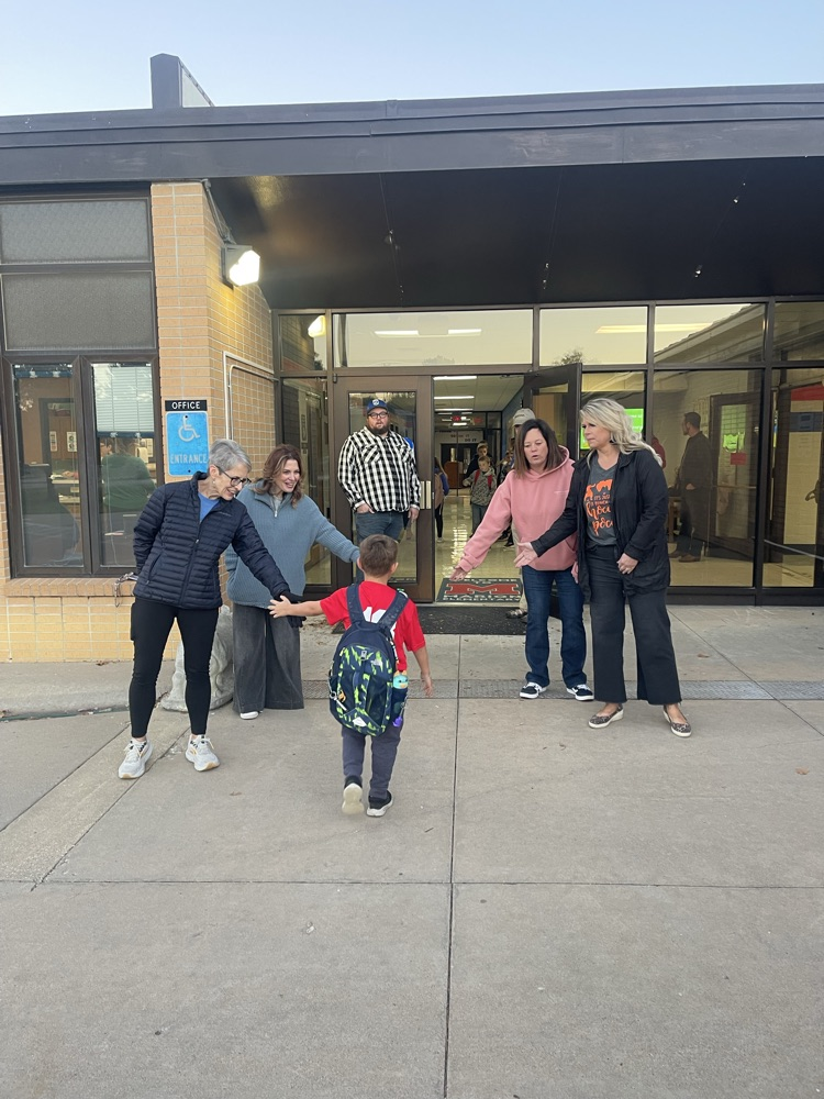 Greeters high five students as they enter the building.