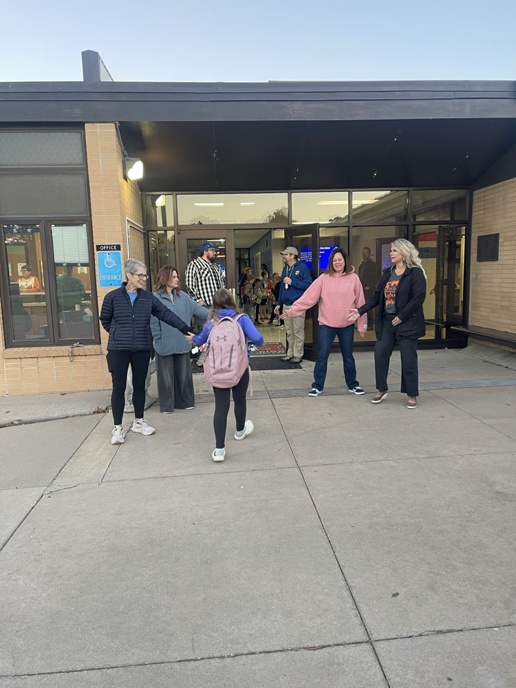 Greeters high five students as they enter the building. 