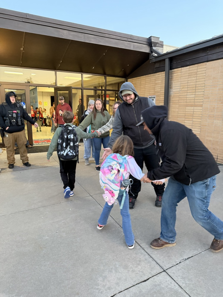 .Greeters give high fives as students enter the building