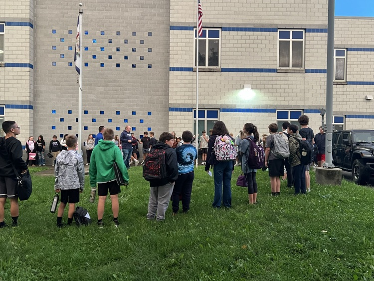 students gathered around flag pole