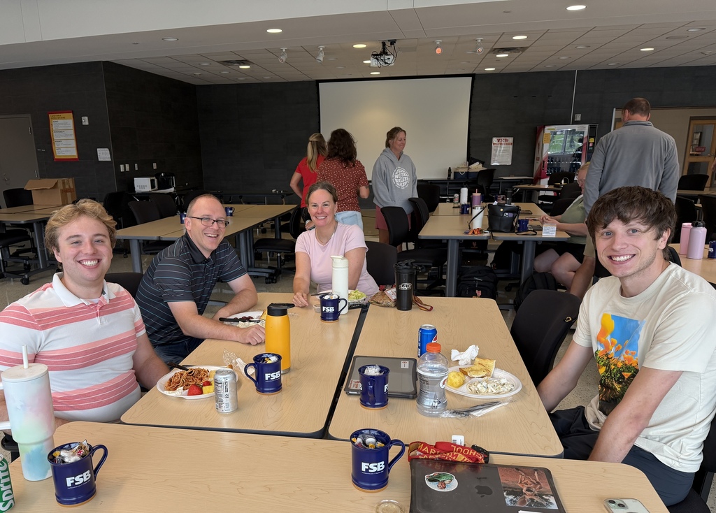 Staff members smiling for a picture while enjoying lunch. 