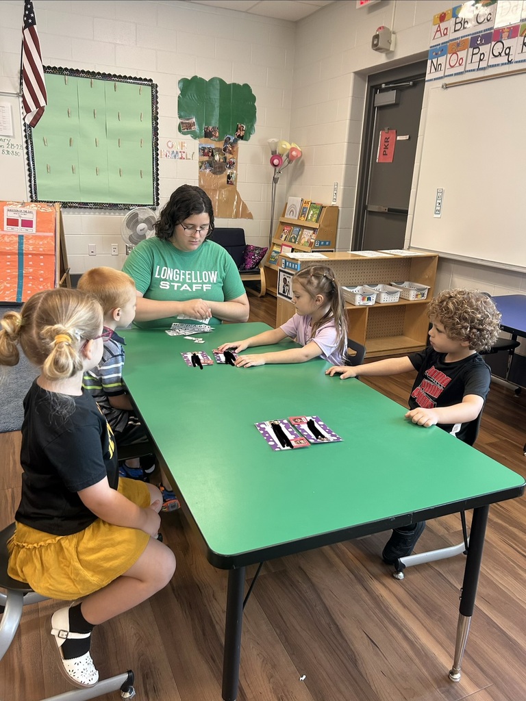 An associate helps facilitates an activity with four students sitting at a table. 
