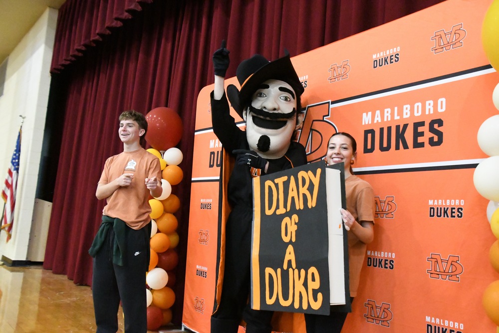 mcsd duke mascot holding giant book