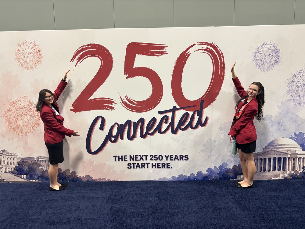 two middle school girls posing with banner