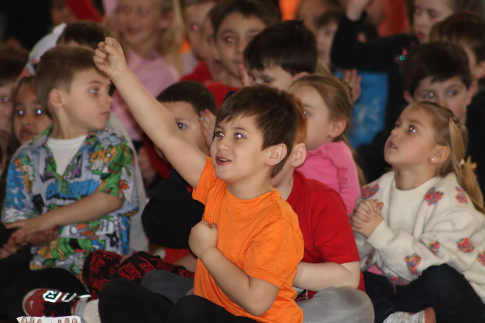 A student sitting and raising his arm in the air