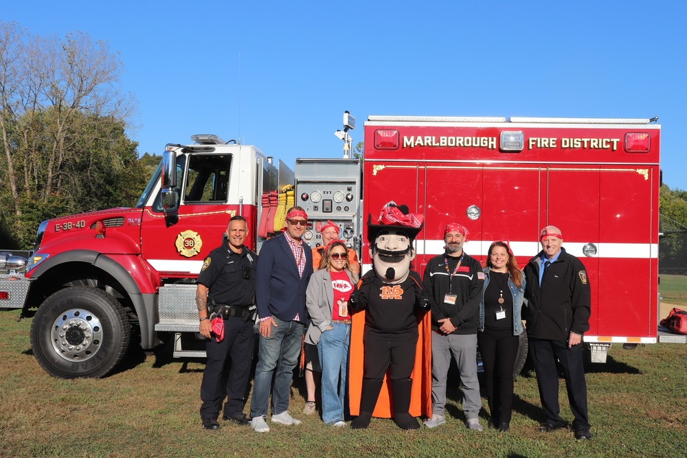 School and community leaders stand in front of a fire truck