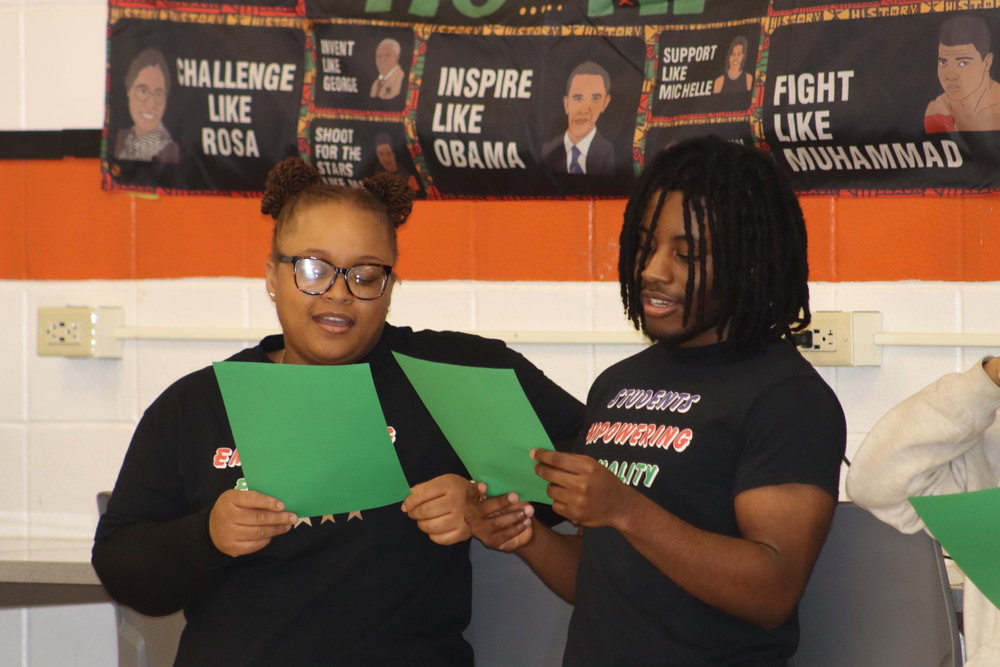 Two students reading off papers