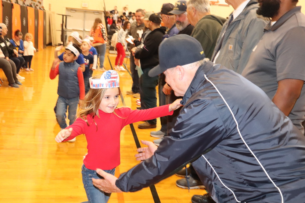 A student goes to hug a veteran