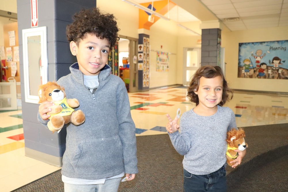 Two students holding stuffed lions