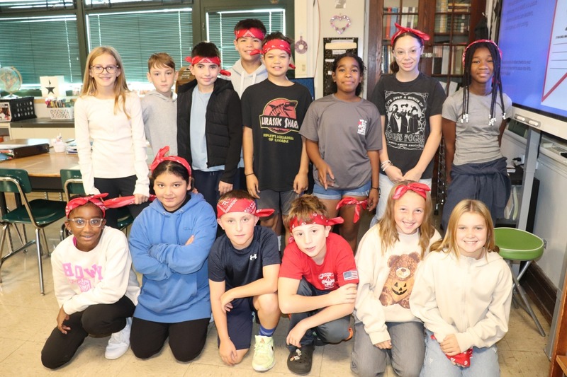 Students pose wearing red bandanas