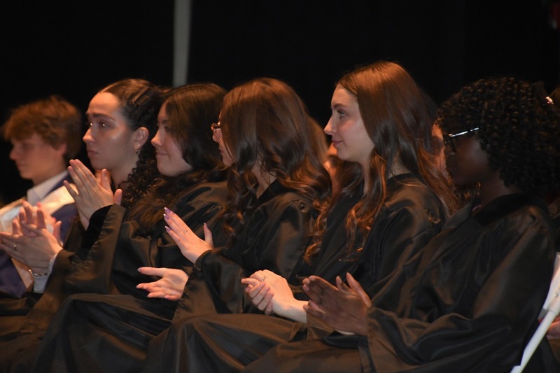 student in black robes clapping