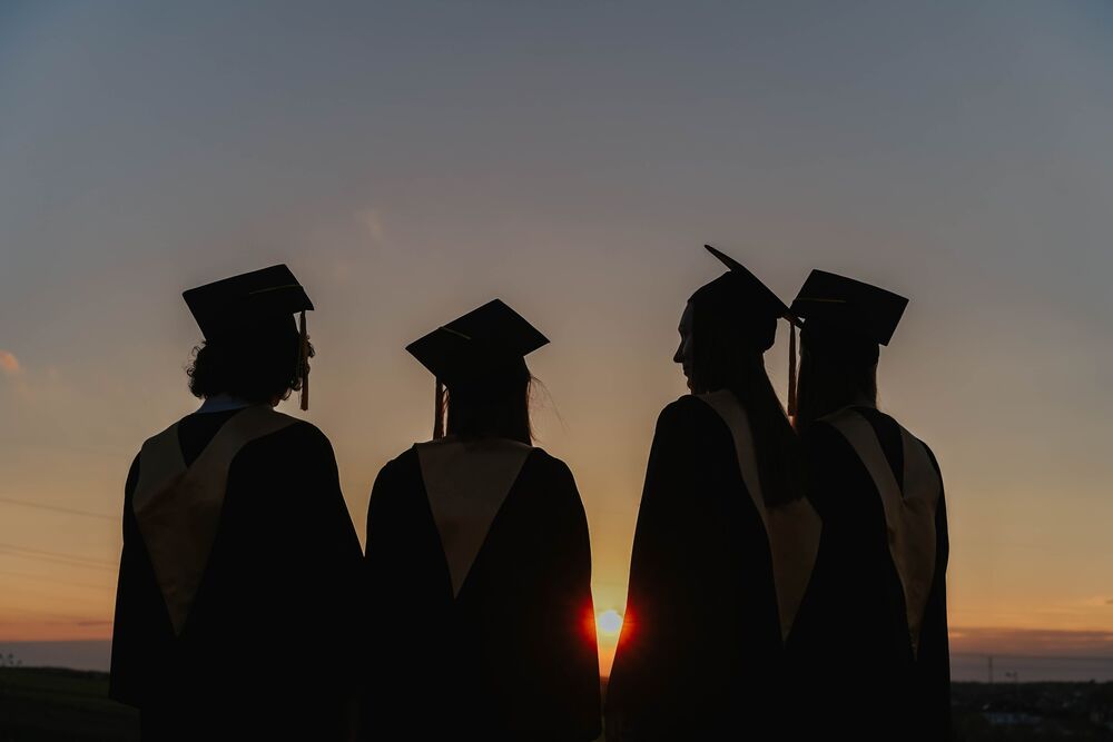 Graduation picture. Four graduates standing wearing their hats. 