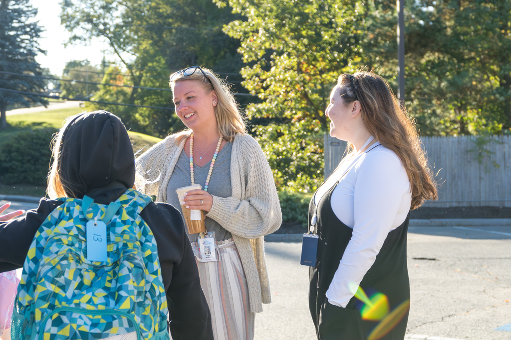 Two Richer School teachers smile and talk to students outside.