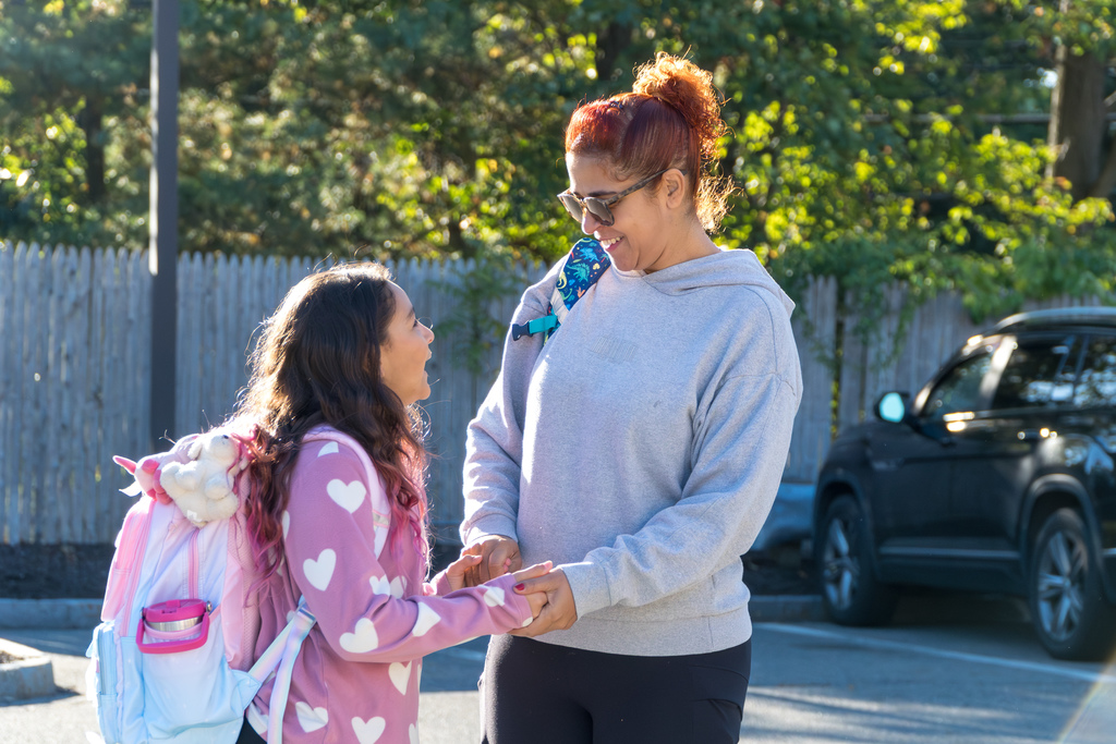 A Richer School student and her mom hold hands and smile outside.