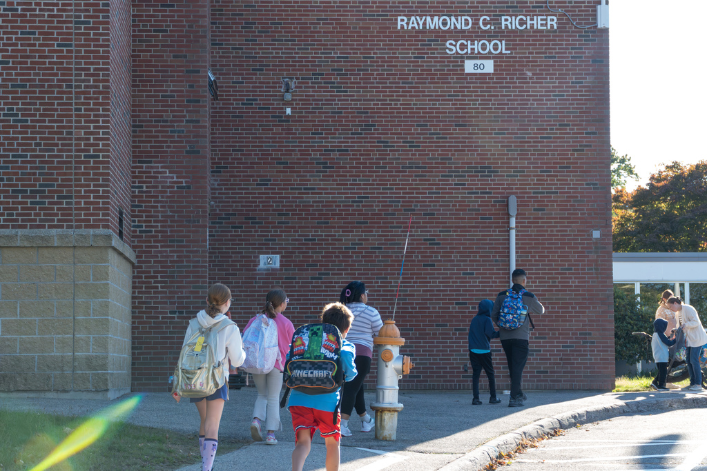 Students and family members walk on the sidewalk outside the Richer School.