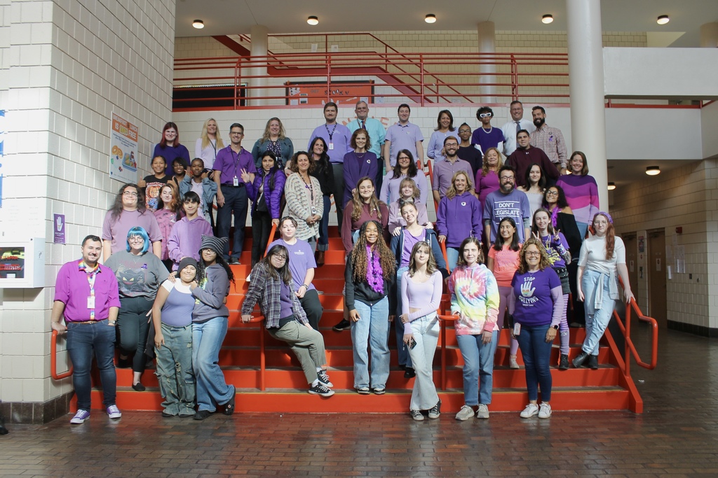  Over forty Marlborough High School employees and students wearing purple pose for a group photo on a staircase inside the high school.