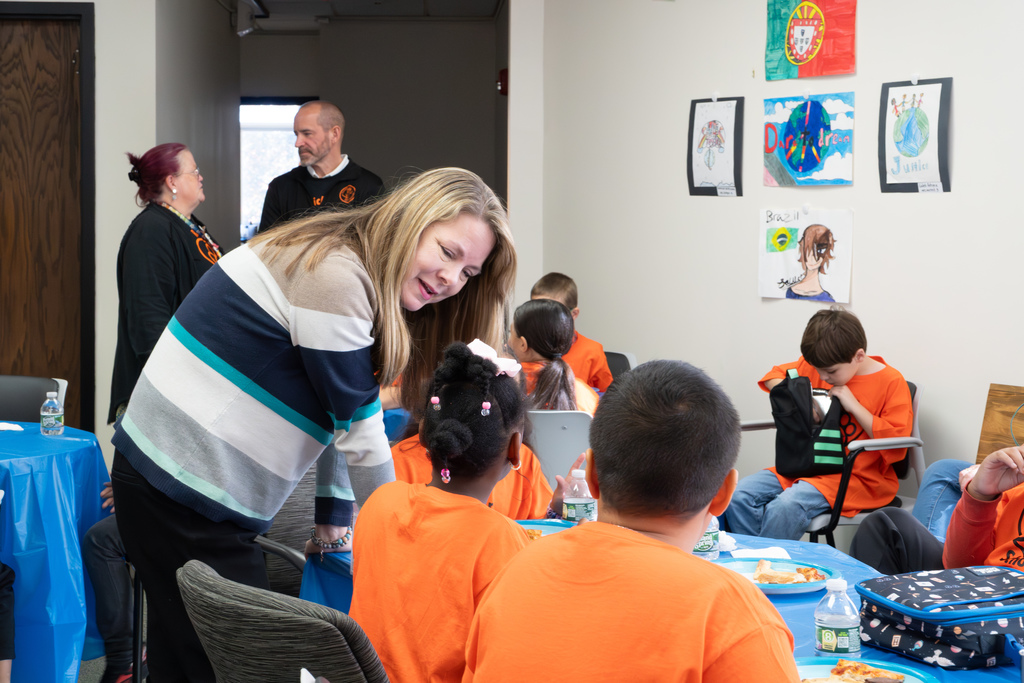 A court staff member chats with two Richer School students sitting at a table.