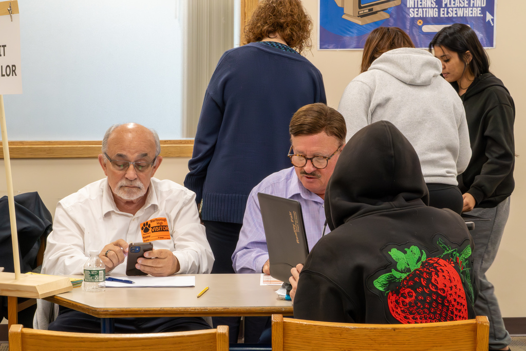 Two volunteer credit counselors help a student review their budget at the 2025 MHS Reality Fair.