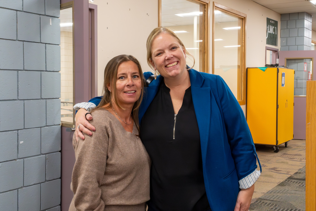 Two women smile and pose for a group photo.