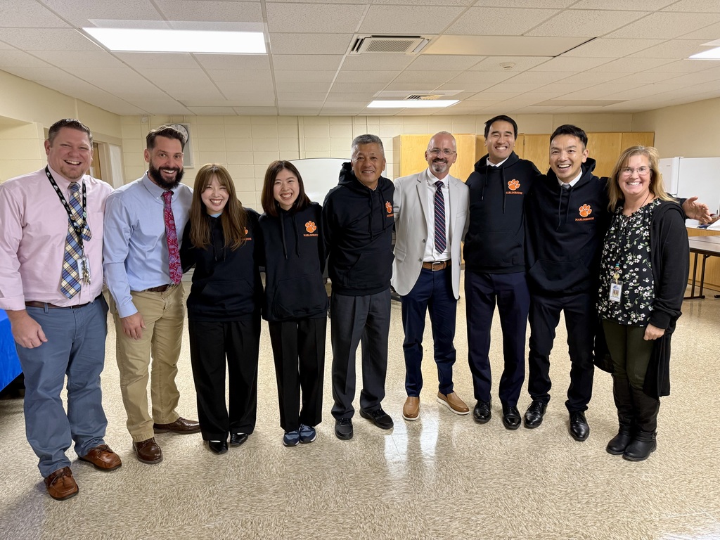 MPS DEC staff pose with Japanese guests from the Akiruon Exchange Program wearing black hoodies with the Panther logo.
