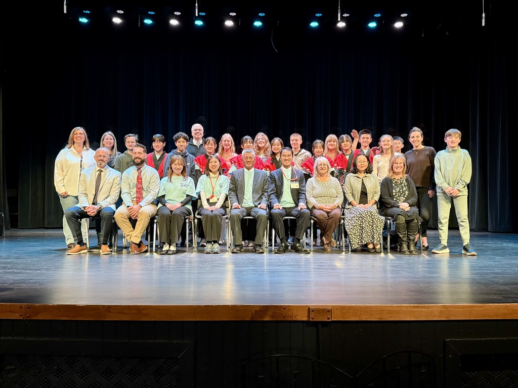 MPS students, staff, and faculty members, along with Japanese guests, pose for a group photo on the Whitcomb Theatre stage.