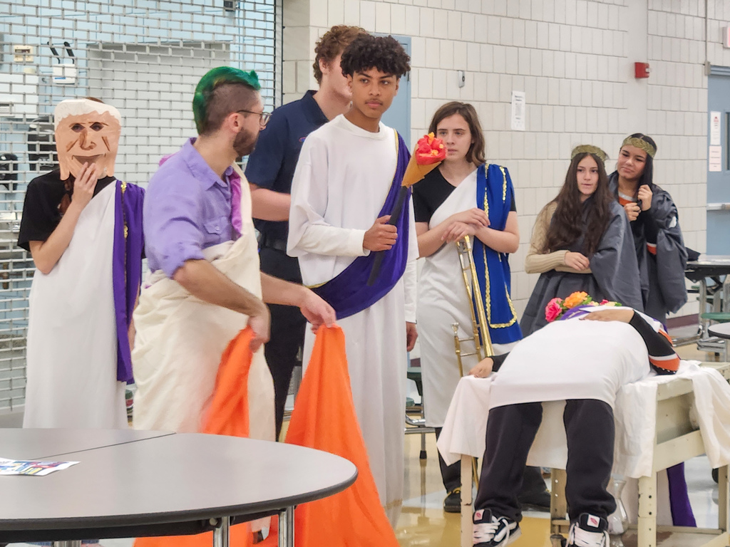 A teacher and students perform a Roman play in a cafeteria.