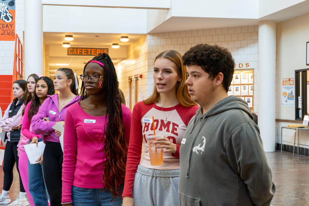 Three MHS students talk as they stand in a hallway.