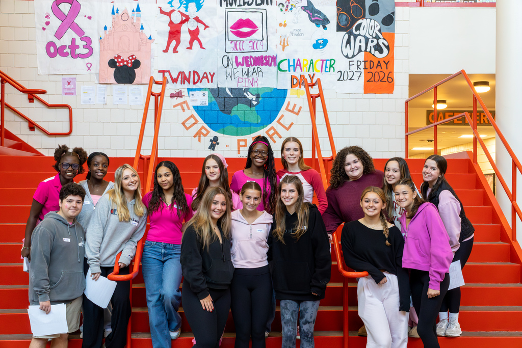 A group of MHS volunteer tour guides pose for a photo on a staircase.