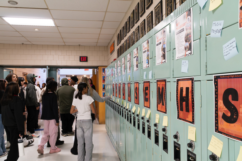 8th-grade students read testimonials from high school students posted on sticky notes on the #ChooseMHS wall.
