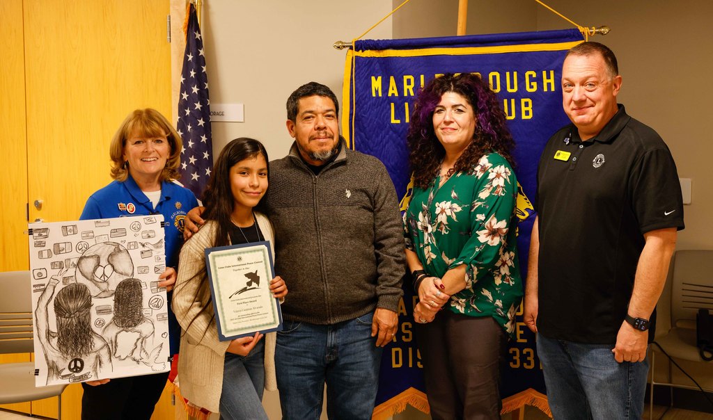 Student Valeria, her father, Laura Koester, Ms. Zouharis and a Marlborough Lions Club member pose for a group for photo with Valeria's winning artwork and her certificate.