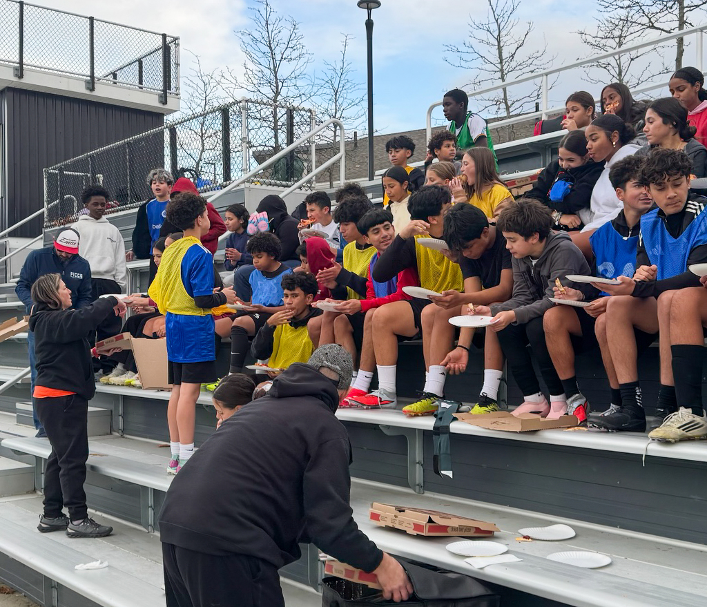  The Whitcomb School soccer team sits on the bleachers, eating pizza.