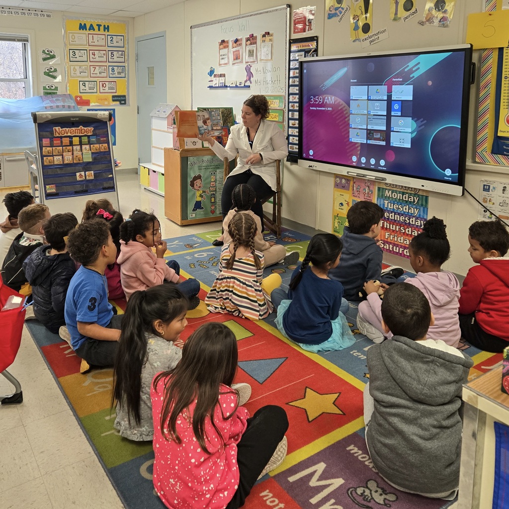 A woman sits and reads to a group of Richer School students.