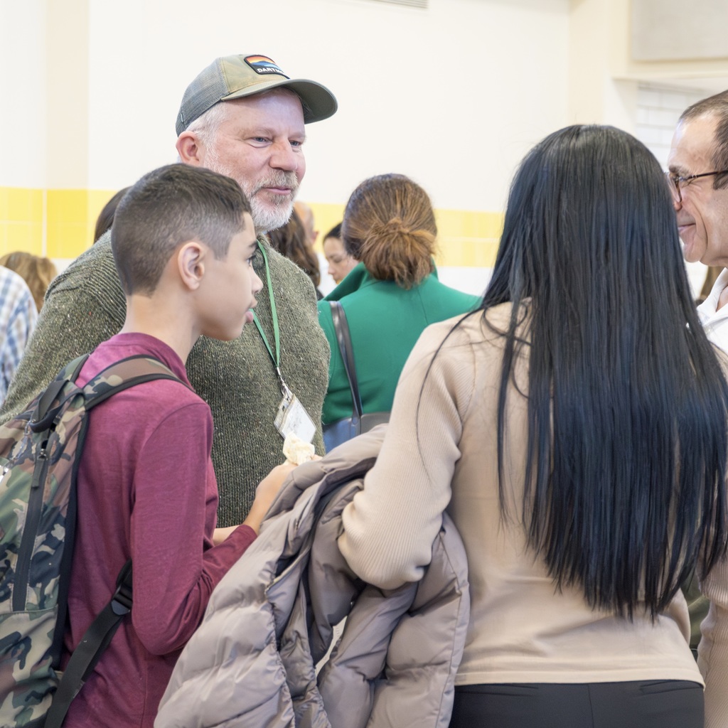 A Whitcomb staff member and student stand, talking to two family members.