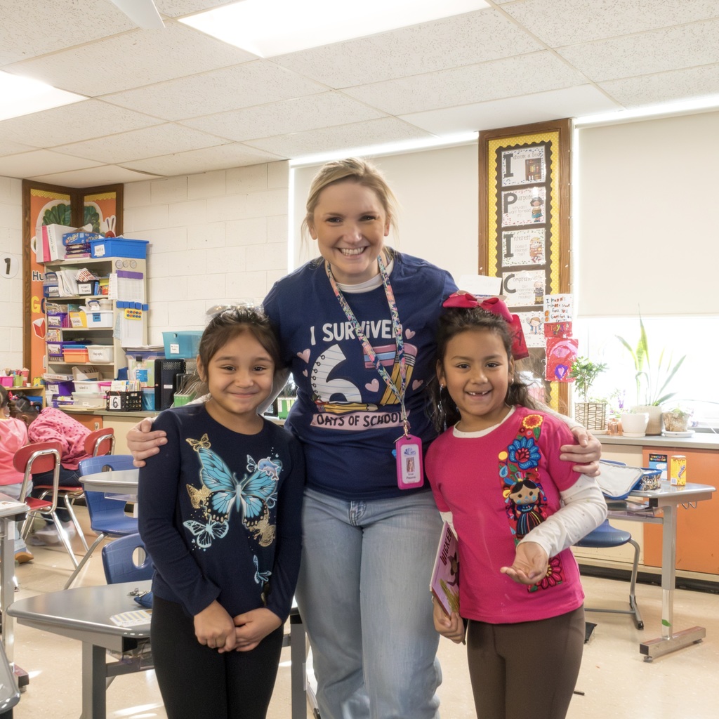 A Kane School teacher wearing a blue shirt that reads "I survived 67 days of school" stands and poses with two female students.
