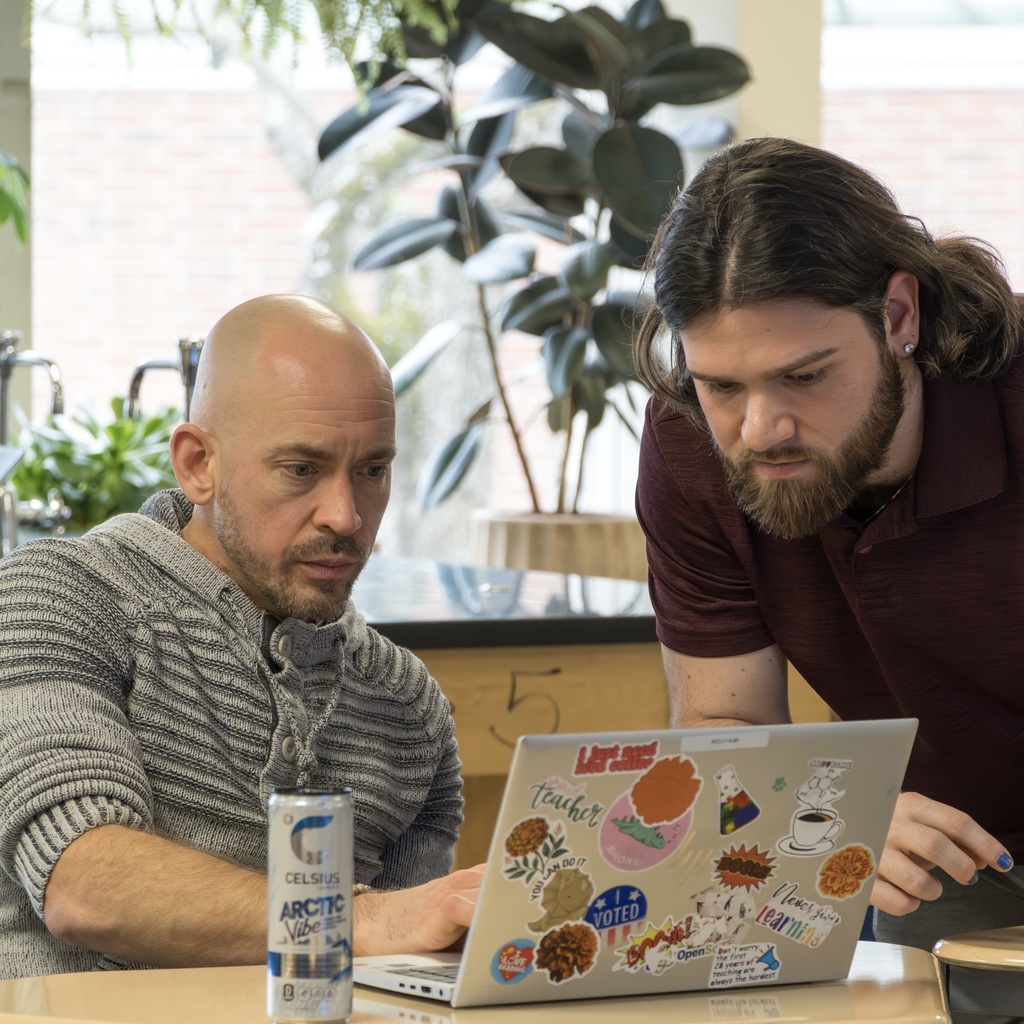 Two Whitcomb staff members work on a laptop.