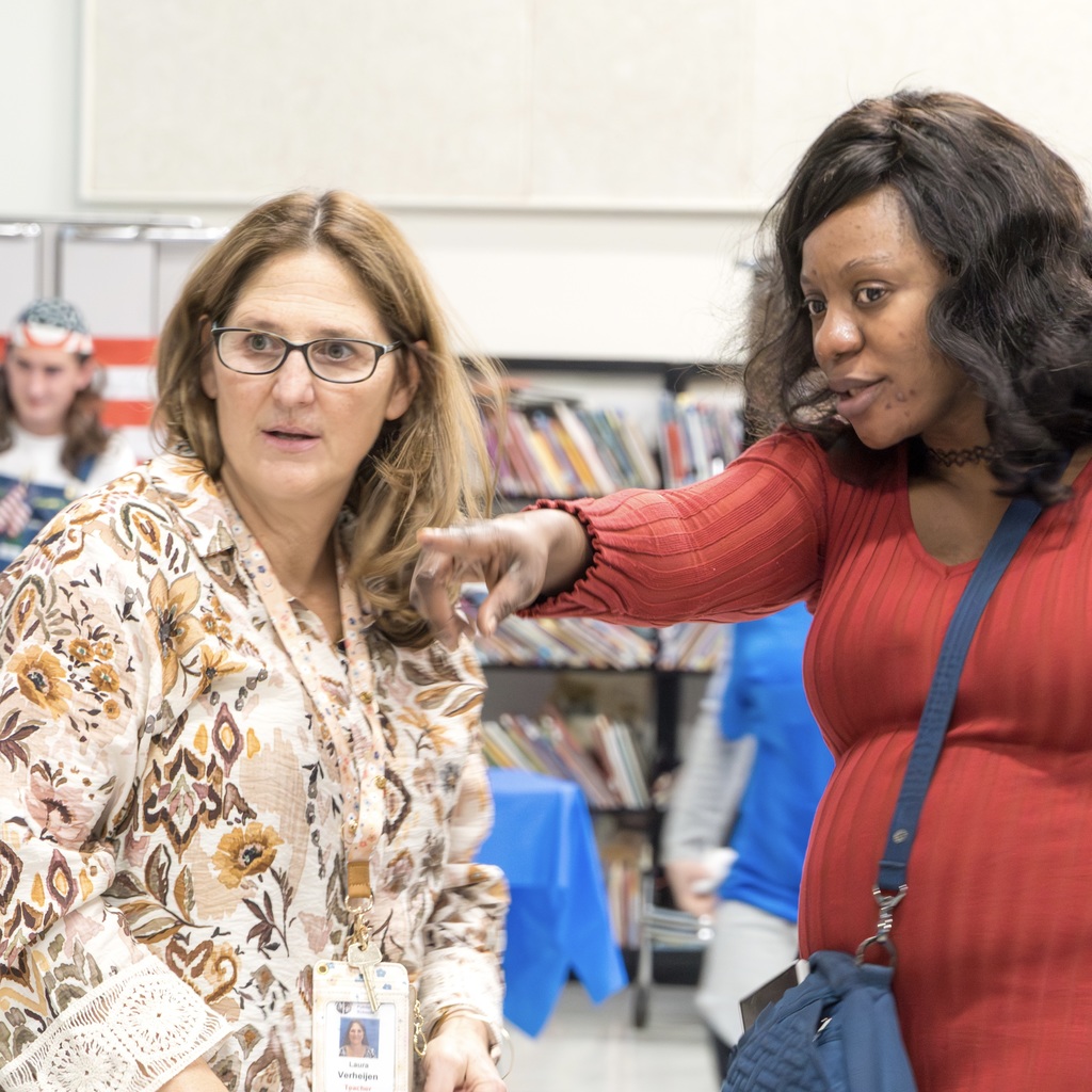A Richer School family member points at something in the distance while talking to a staff member.