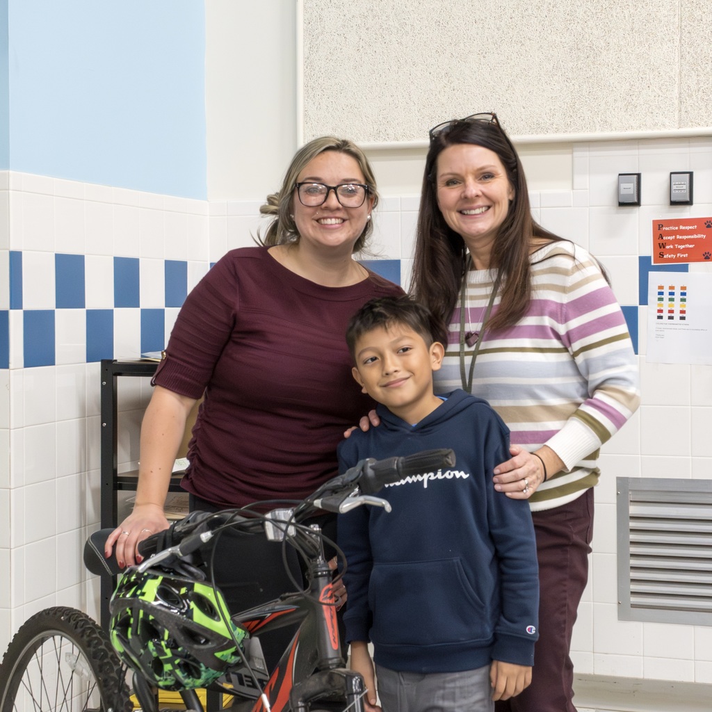 Two Richer School staff and a student pose with his raffle prize, a bike.