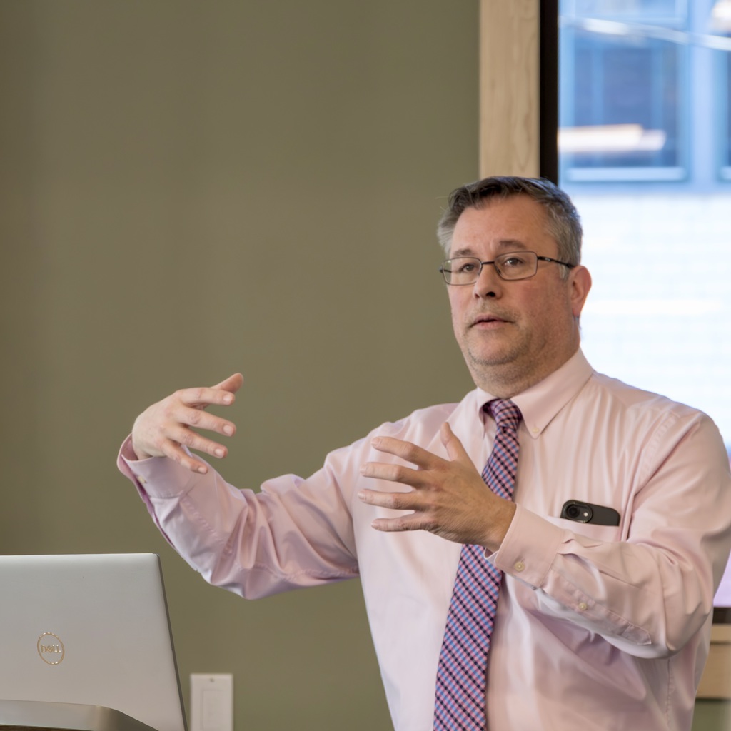 Marlborough High School Principal Stephen Sierpina stands behind a podium with a laptop, presenting to the MEDC board.