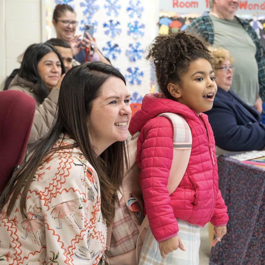 ECC Director Jill Regan kneels down next to a female student who is watching something in awe.