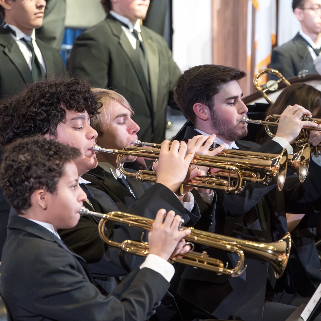Four members of the Marlborough High School band, wearing suits, play their instruments.