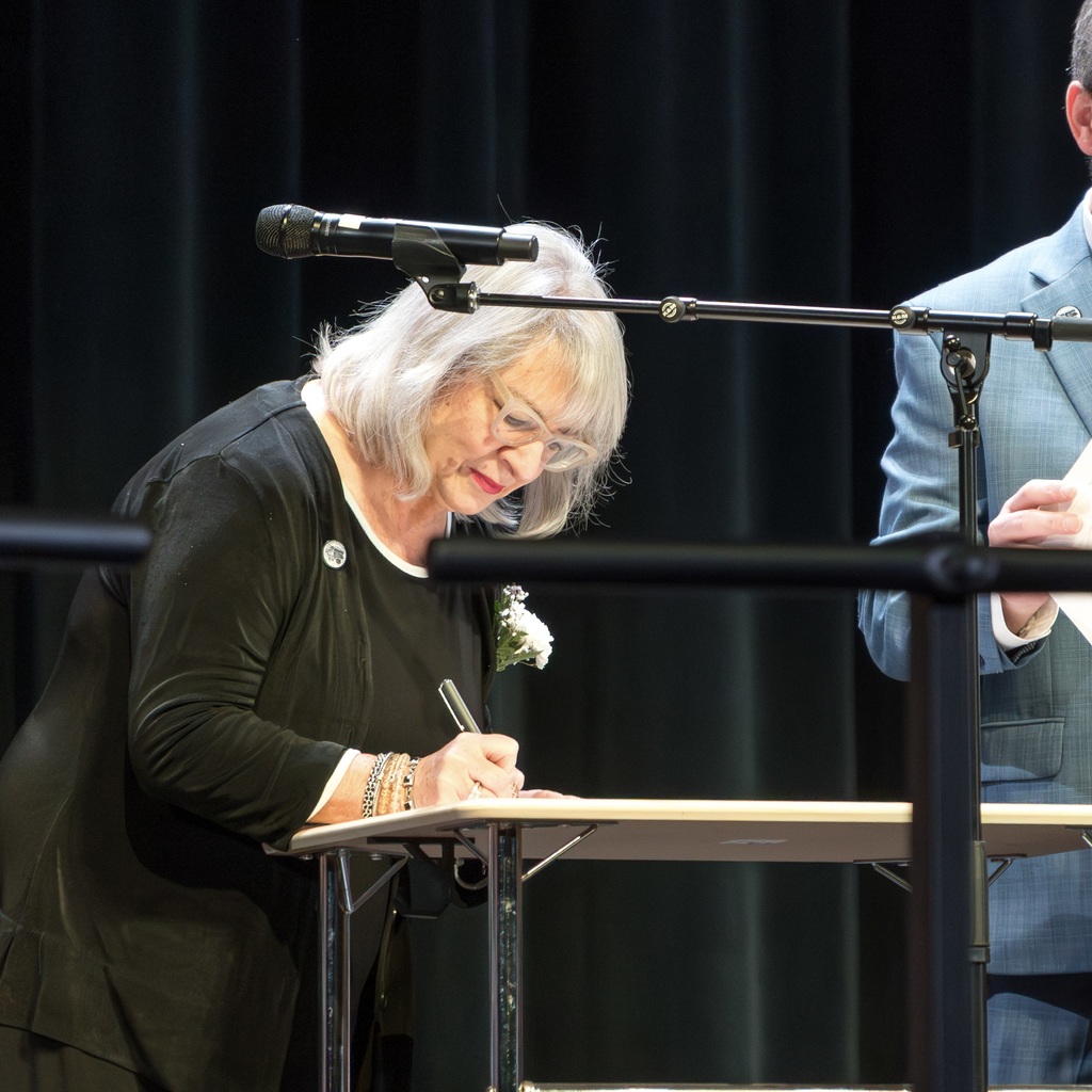 A school committee member signs a document during her inauguration.