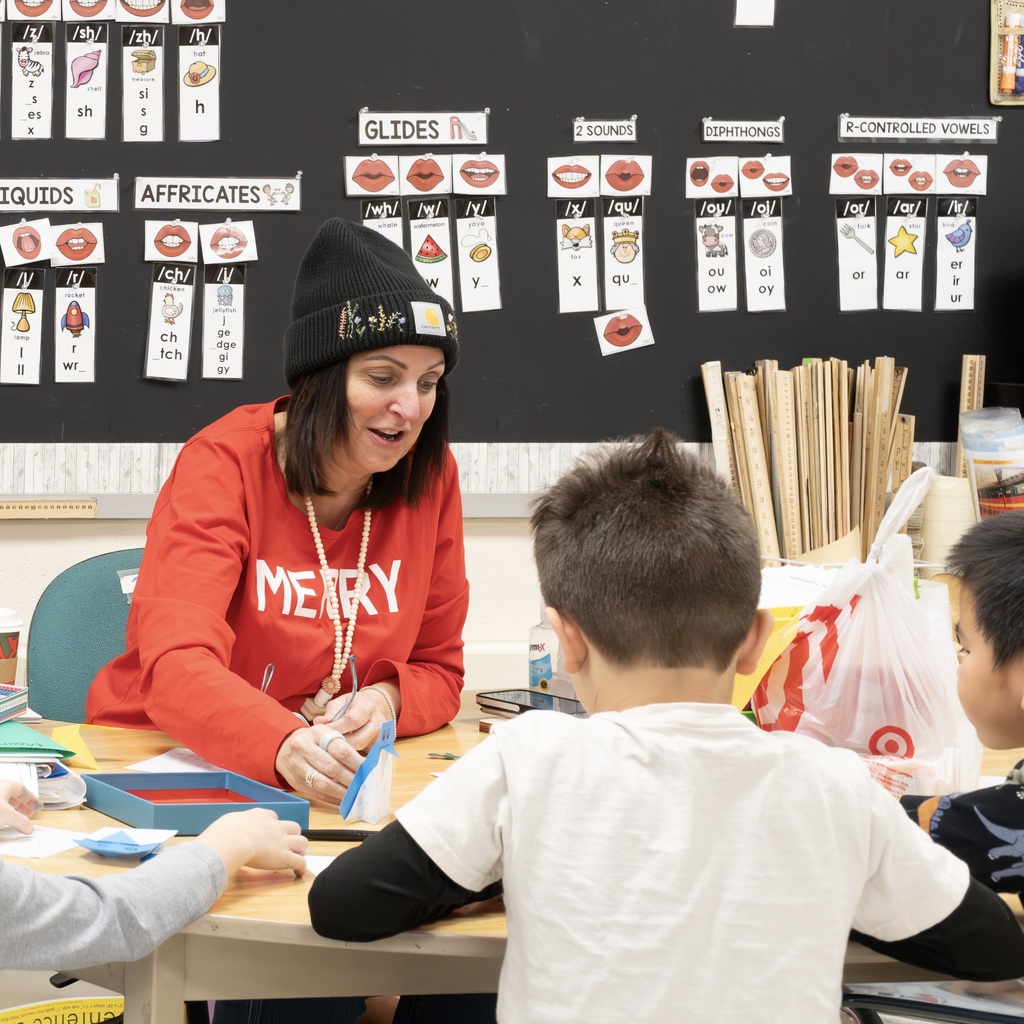 A Jaworek teacher sits at a table. Three students sit across from her, working on crafts.
