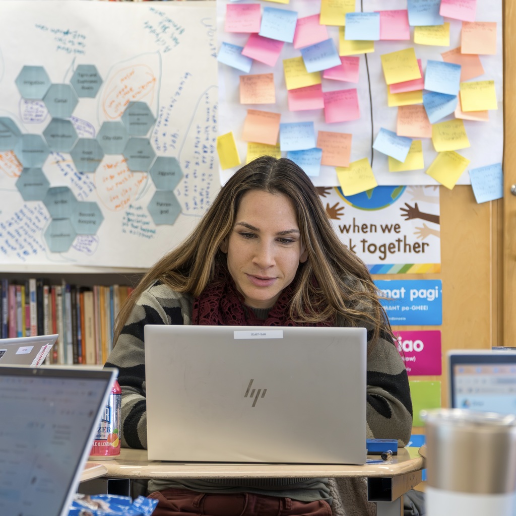 A staff member sits working on her laptop.