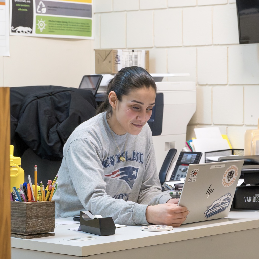 An MHS guidance counselor sits at a desk working on her laptop.