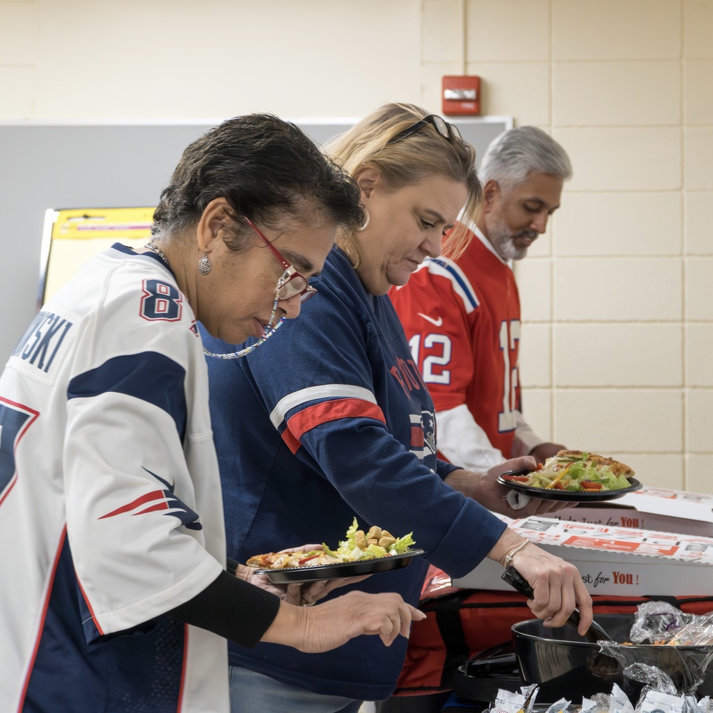Three Marlborough Public Schools employees serve themselves food from a table.