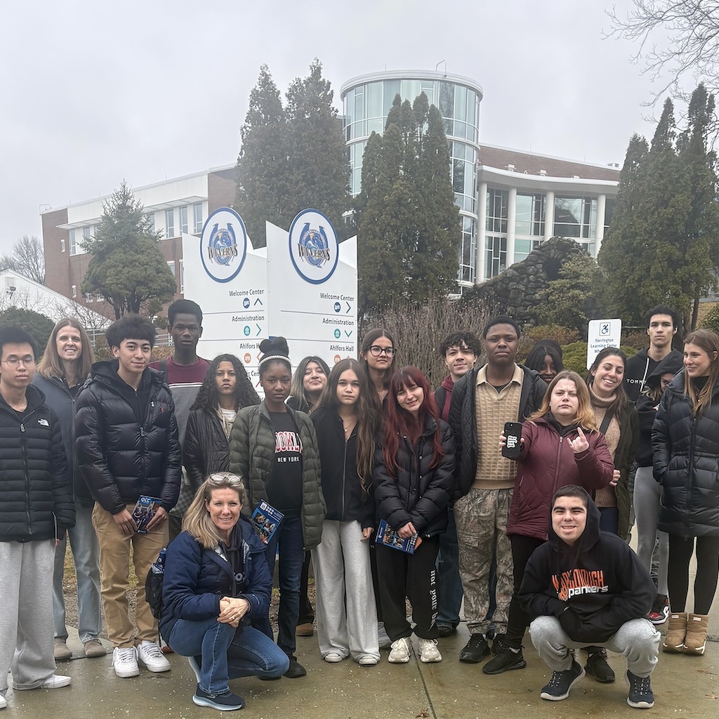 A group of MPS students poses for a photo in front of a building with trees.