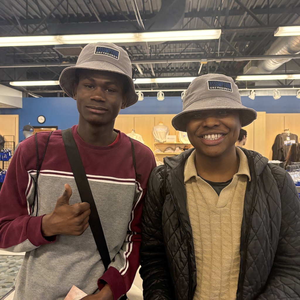 Two MPS students are standing inside a shop, both wearing hats. One with a striped shirt, the other in a jacket.