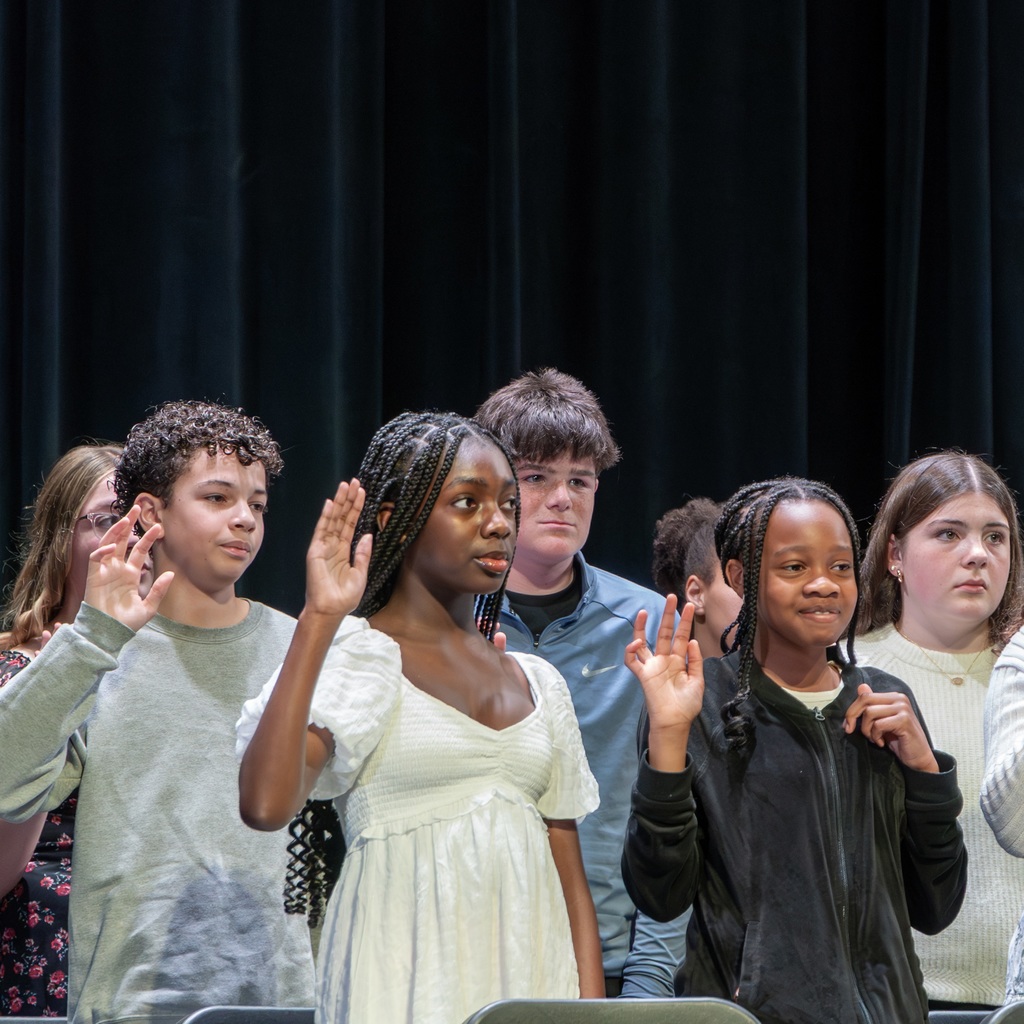 Several Whitcomb students are on stage, with raised hands, possibly during the NJHS oath ceremony.