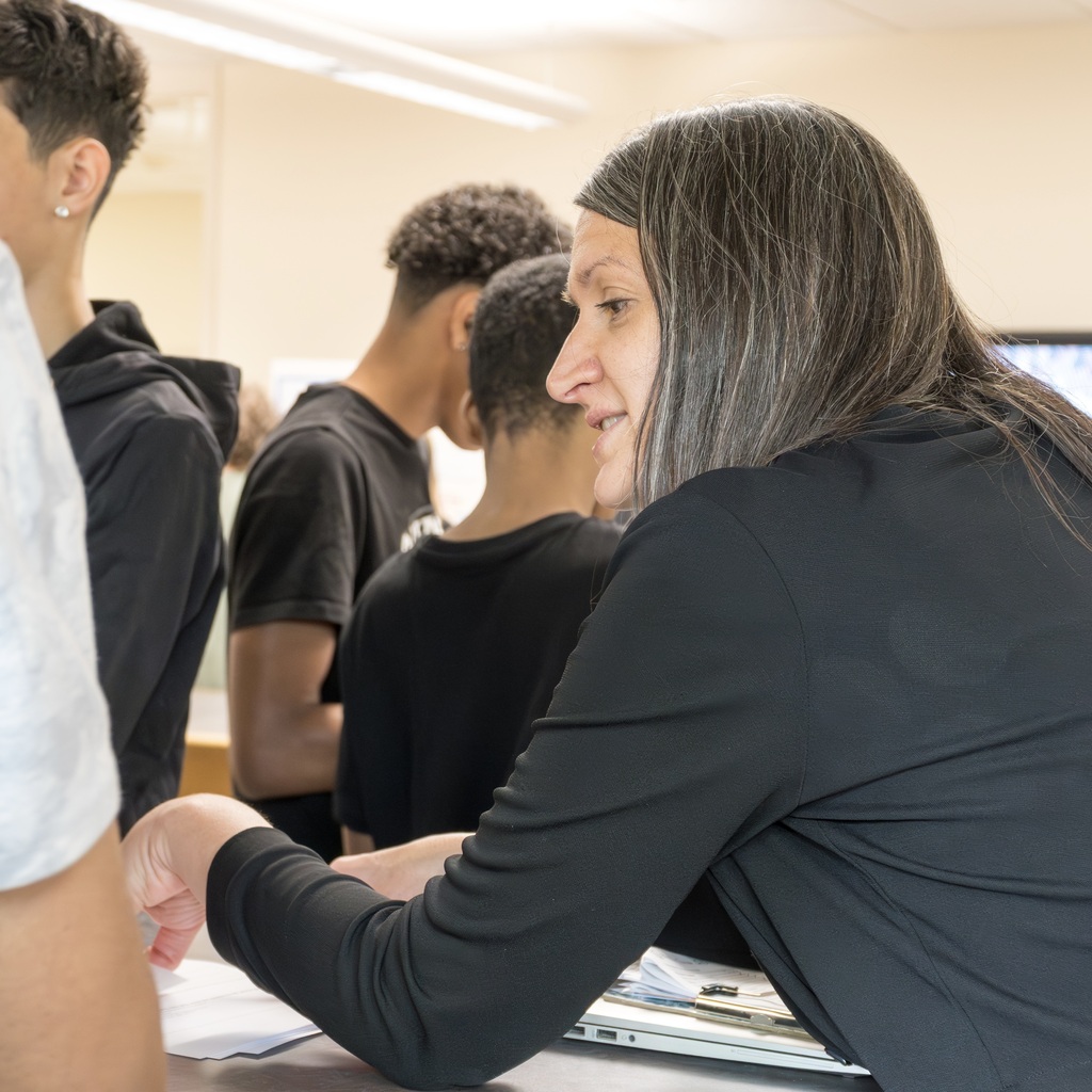 A Whitcomb female staff member talks to the students inside the library.